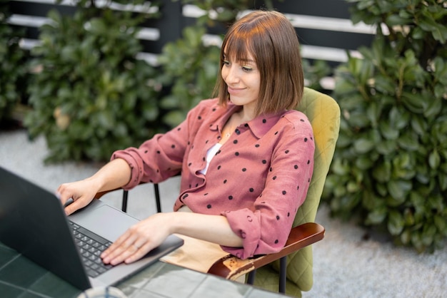 Vrouw werkt op laptop online in de tuin buiten