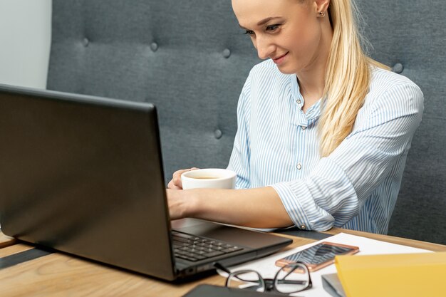 Vrouw werkt op laptop op kantoor aan huis.