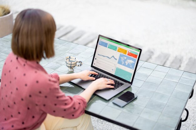 Vrouw werkt op laptop terwijl ze buiten aan tafel zit