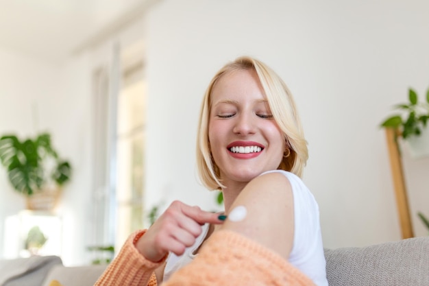 Vrouw wijst naar zijn arm met een verband na ontvangst van het covid-19-vaccin. Jonge vrouw die haar schouder laat zien na het krijgen van een coronavirusvaccin