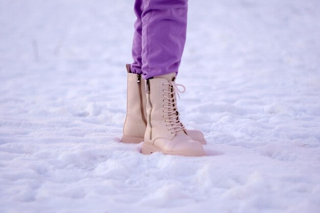 Vrouw winterlaarzen op sneeuw close-up foto van winterschoenen Onscherpe achtergrond Selectieve aandacht