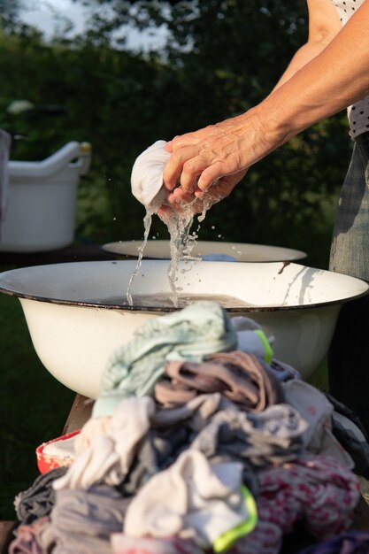 Vrouw wringt natte kleren uit na het wassen met haar handen in een oude bak buiten op het platteland