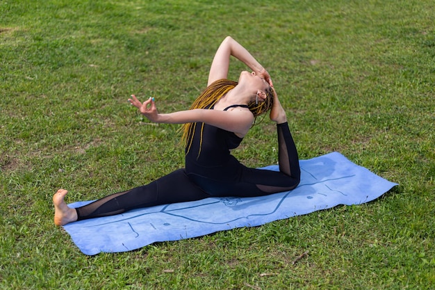 Vrouw yogi met dreadlocks die koningsduif Eka Pada Rajakapotasana oefent, pose op yogamat