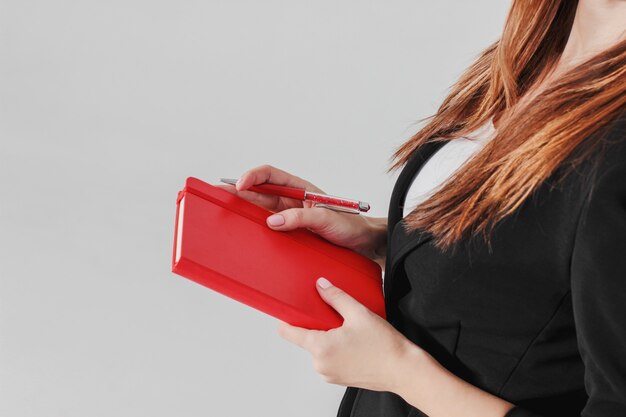 Vrouw zakelijke dame in zwart pak met rode dagboek planner in de hand