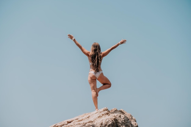 Vrouw zee yoga achteraanzicht van vrije kalme gelukzaligheid tevreden vrouw met lang haar op de top van de rots met