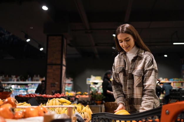 Vrouw zet bananen in een kar tijdens het winkelen