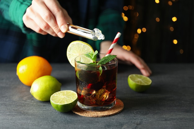 Vrouw zet ijs in een glas Cuba Libre