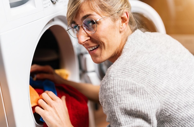 Vrouw zet kleren uit wasmachine of droger thuis wasservice