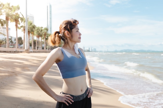 Vrouw zet masker af en rust na het joggen aan het strand in de zomer