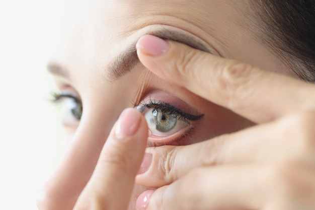 Vrouw zet regels voor zachte contactlenzen op voor het dragen van contactlenzenconcept