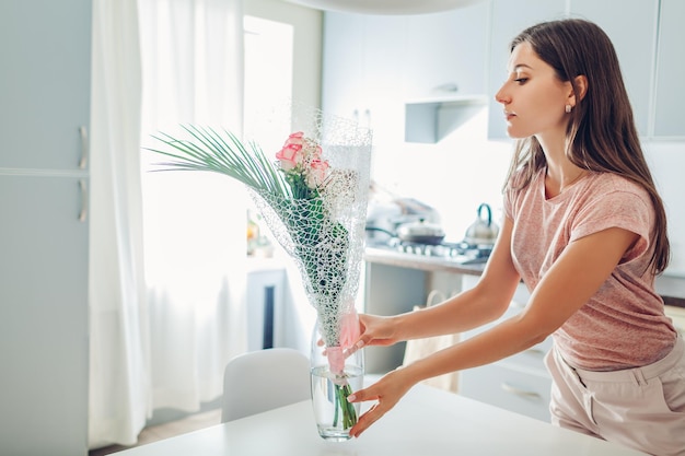 Vrouw zet vaas met bloemen huisvrouw die voor gezelligheid zorgt in de keuken