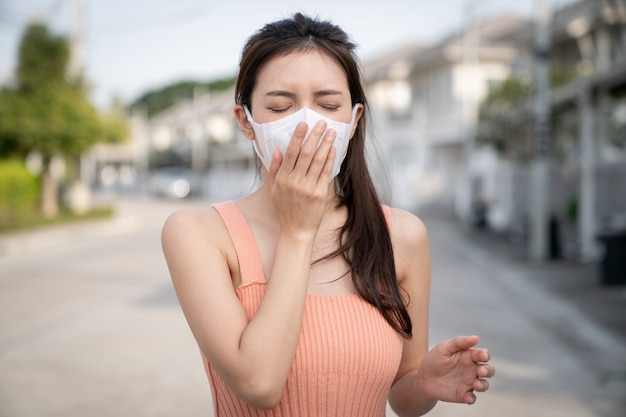 Vrouw ziek voelen, hoesten of niezen. ze draagt een beschermend masker.