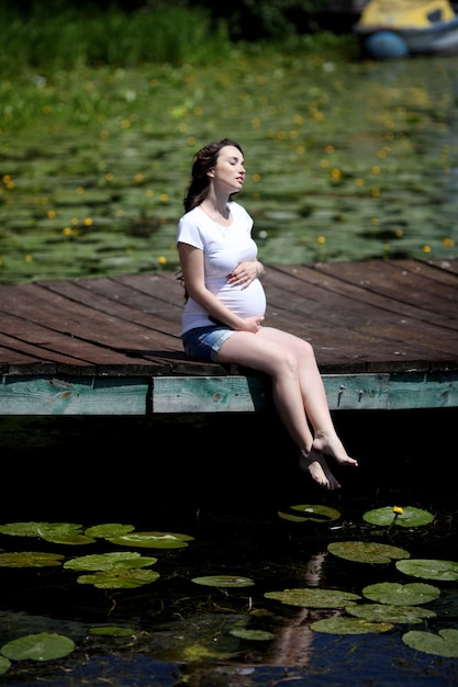 Vrouw zit aan steiger zomerdag aan de oever van het meer