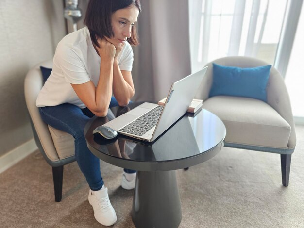 Vrouw zit aan tafel met een laptop