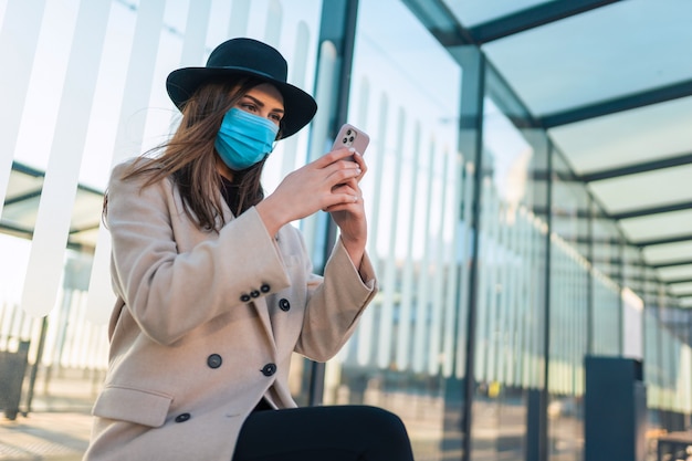 Vrouw zit bij bushalte tijdens pandemie