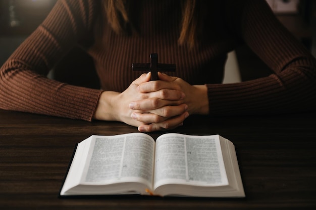 Vrouw zit en bestudeert de Schriften Het houten kruis in de handen Christelijke onderwijsconcepten De Heilige Schrift opent en bidt tot God