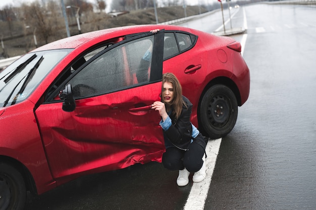 Vrouw zit in de buurt van een kapotte auto na een ongeval. roep om hulp. autoverzekering