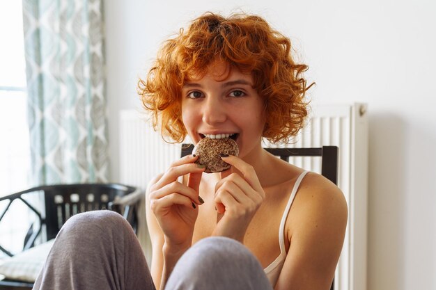 Foto vrouw zit in een stoel en eet koekjes.