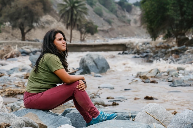 Vrouw zit met haar rug naar de oever van een machtige rivier