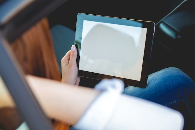 Vrouw zit op de achterbank van de auto met een tablet