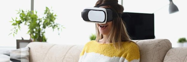 Vrouw zit op de bank en draagt een vr-bril modern apparaat geniet van vrije tijd in de verbeeldingswereld