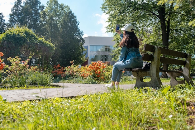 Vrouw zit op de bank in het openbare stadspark en leest een elektronisch boek