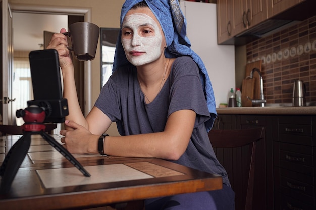 Foto vrouw zit op de keuken en maakt een masker van groene klei