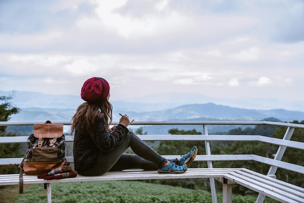 Vrouw zit op een bank op de berg en de lucht