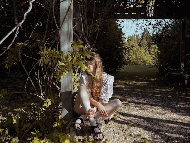 Foto vrouw zit op een plant tegen bomen.