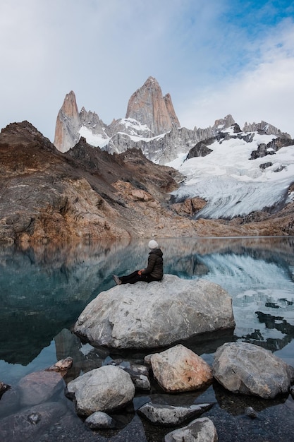 Foto vrouw zit op een steen en kijkt naar fitz roy.