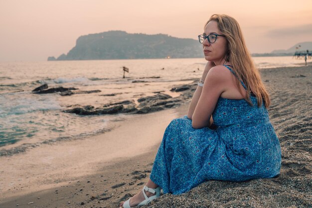 Vrouw zit op het strand en kijkt naar de zee in Alanya stad Turkije reizen of vakantie concept