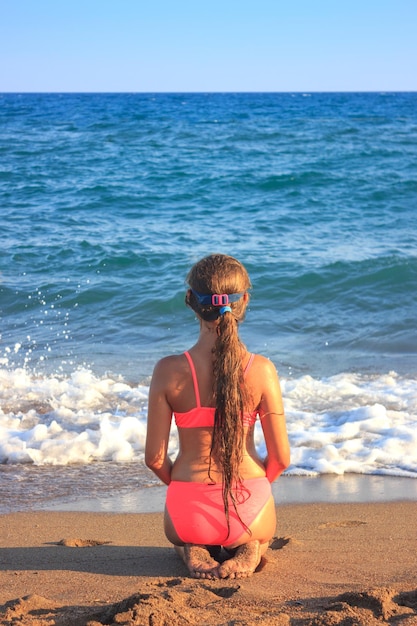 Vrouw zit op het strand tegen de lucht.