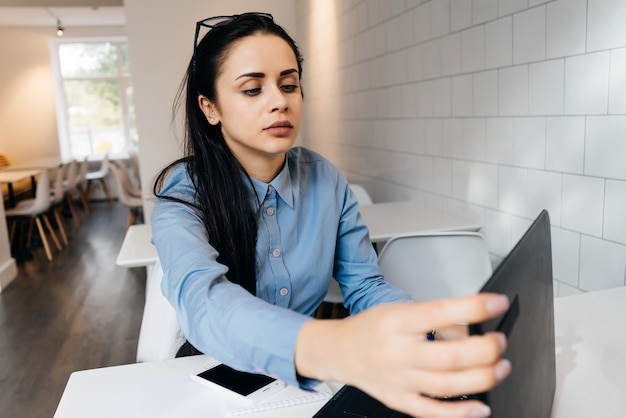 Vrouw zit op kantoor aan tafel en kijkt naar de laptop