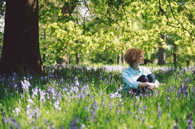 Foto vrouw zit te midden van planten in het bos.