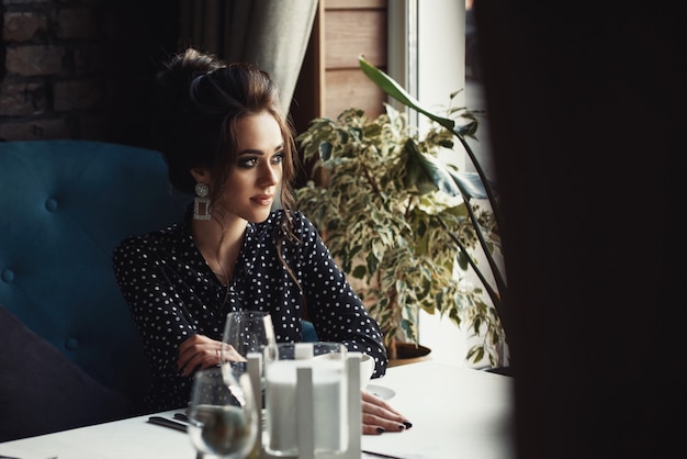 Vrouw zitten aan de tafel in café of restaurant kijkt naar het raam en koffie drinken