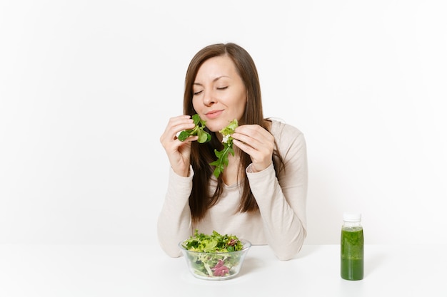 Vrouw zitten aan tafel met groene detox smoothies, salade in glazen kom, handen geïsoleerd op een witte achtergrond. Goede voeding, vegetarisch eten, gezonde levensstijl, dieetconcept. Gebied met kopie ruimte.