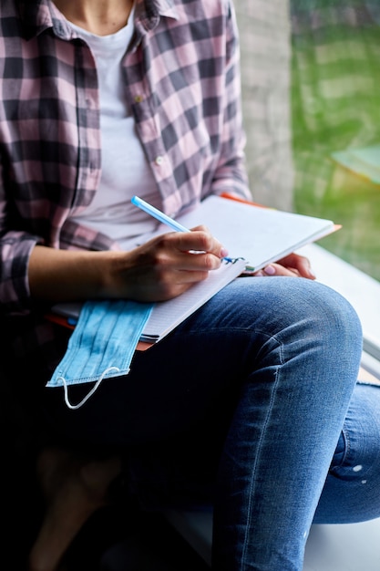 Vrouw zitten bij het raam, schrijven in notitieblok plan