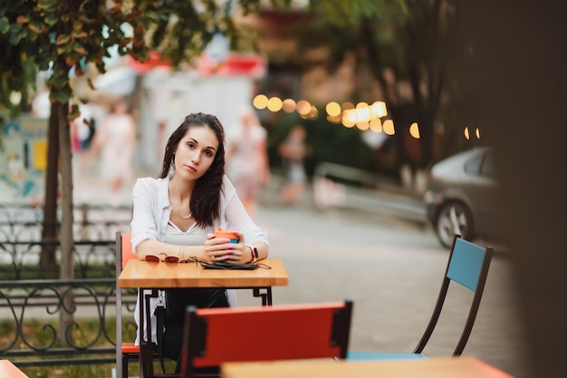 Vrouw zittend aan een tafel op straat. 'S avonds warme stad. Hoge kwaliteit foto