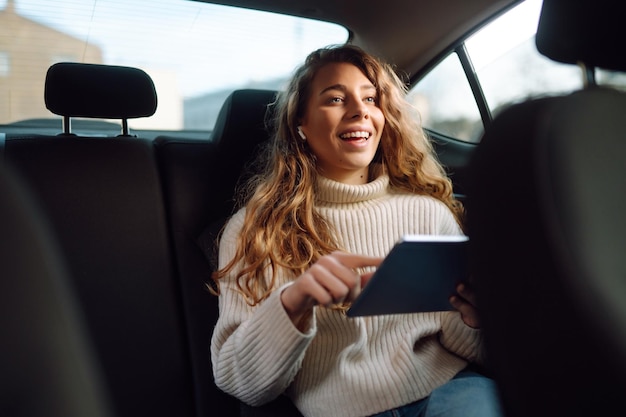 Vrouw zittend op de achterbank van de auto met tablet in de hand Zakelijke taxitechnologie online concert