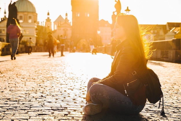 Vrouw zittend op de grond bij zonsopgang bij de Karelsbrug in Praag kopieer ruimte