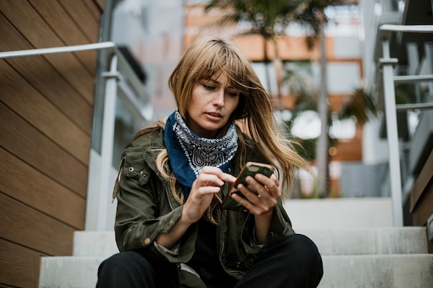 Vrouw zittend op de trap met behulp van een mobiele telefoon tijdens de uitbraak van het coronavirus