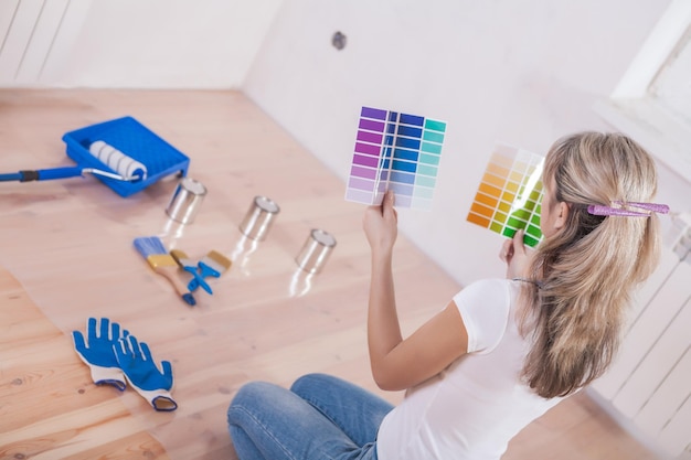 Vrouw zittend op de vloer en kleur selecteren voor muur met palet