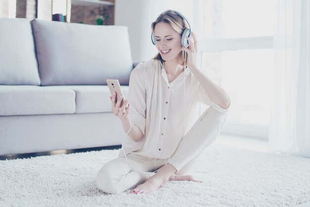 Vrouw zittend op de vloer luisteren naar muziek op de koptelefoon