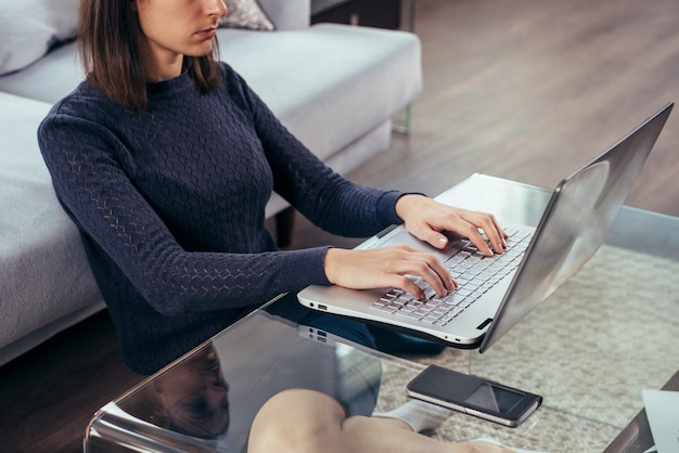 Vrouw zittend op de vloer thuis met behulp van notebook.