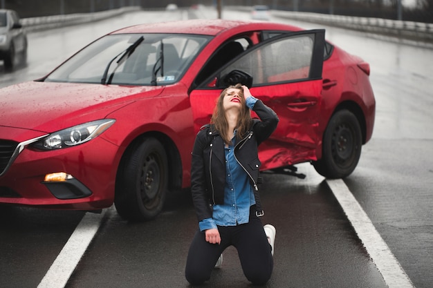 Vrouw zittend op de weg na een ongeval. Gewonde vrouw die zich slecht voelt na een auto-ongeluk