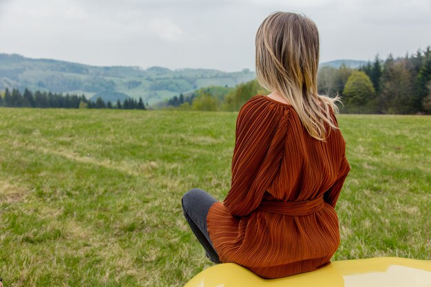 Vrouw zittend op een auto in de tijd van een vakantie in de bergen, Polen. Lente tijd