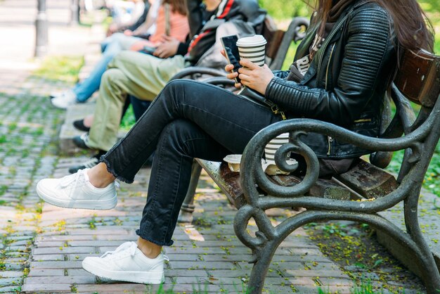 Vrouw zittend op een bankje in het stadspark koffie drinken op internet surfen via mobiel