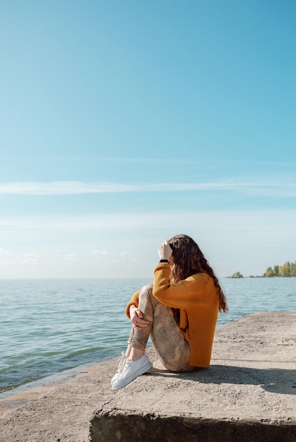 Vrouw zittend op een stenen trap op een strand haar knieën knuffelen