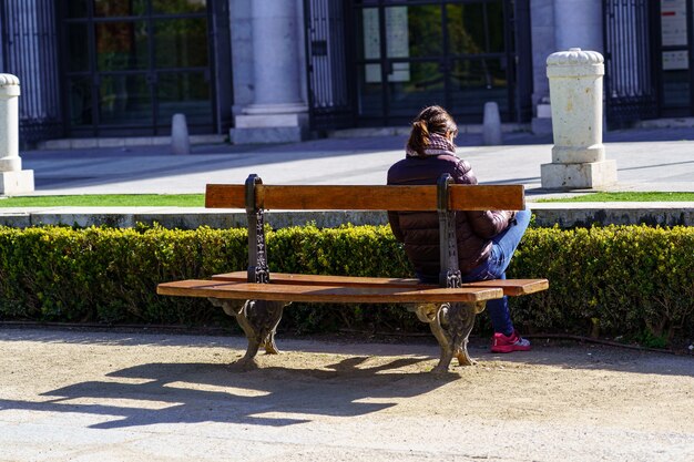 Vrouw zittend op haar rug op een bankje in een openbaar park, genietend van een zonnige dag. Madrid.