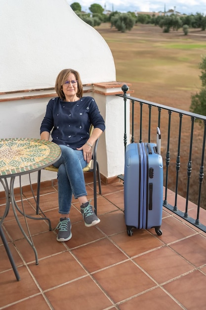 Vrouw zittend op het balkon van haar appartement bij aankomst op haar vakantieplek om te genieten van een paar relaxte dagen